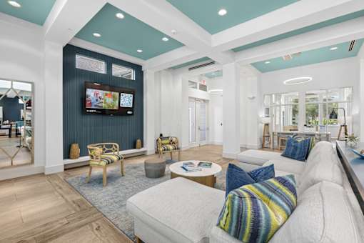 A living room with a white couch and a television on the wall.
