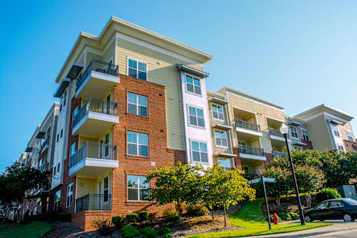 A multi-story apartment building with balconies and a clear blue sky above.