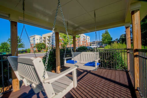 A porch swing hangs from a chain on a wooden porch.