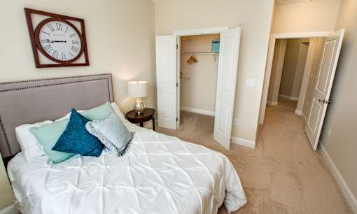 A bedroom with a large bed and a clock on the wall.