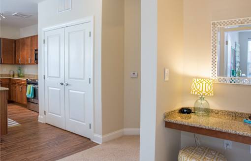 A kitchen with a white door and a counter with a lamp on it.