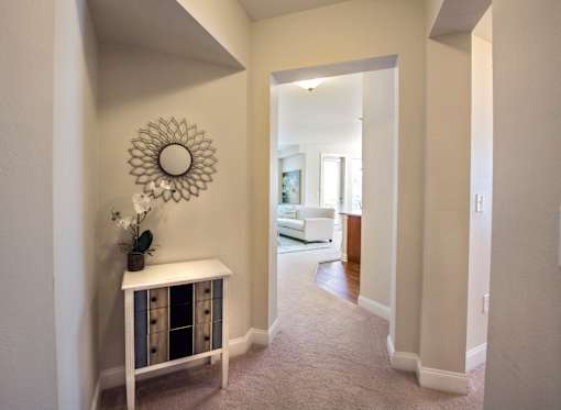 A hallway with a white console table and a mirror on the wall.