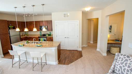 A kitchen with a white island and bar stools.