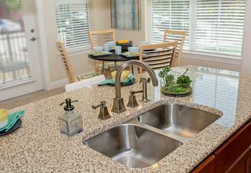 A kitchen with a granite countertop and a stainless steel sink.