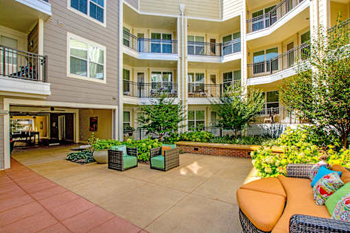 A courtyard with a couch and chairs surrounded by apartment buildings.