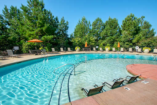 A large outdoor swimming pool with a wooden deck and lounge chairs.