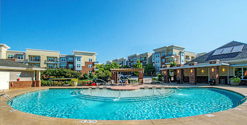 A large swimming pool in front of apartment buildings.