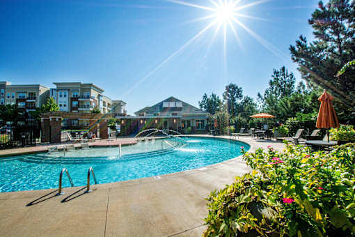 A sunny day at a poolside with a building in the background.