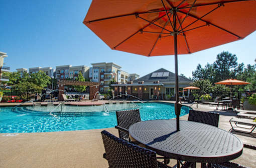 A patio with a table and chairs under an orange umbrella.
