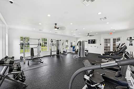 A gym with a variety of equipment including treadmills, weights, and exercise machines.