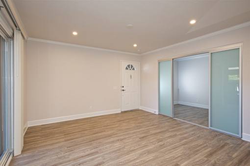A room with wooden flooring and a sliding glass door.
