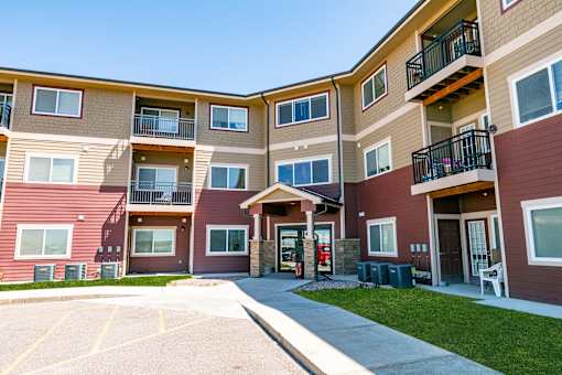 Apartment building with a parking lot in front.