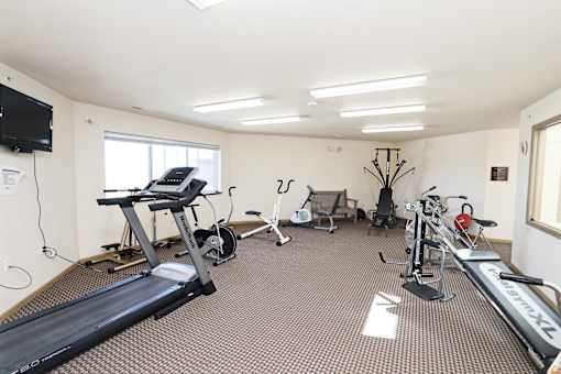 A spacious gym with a variety of equipment including treadmills, stationary bikes, and a television.