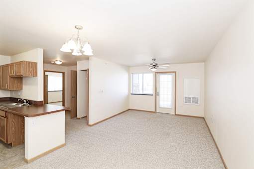 A spacious living area with a kitchen and a ceiling fan.