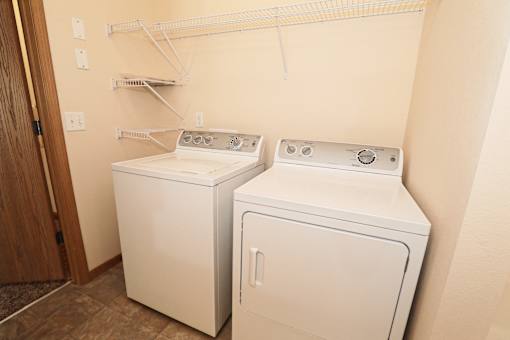 Two white front loading washing machines in a laundry room.