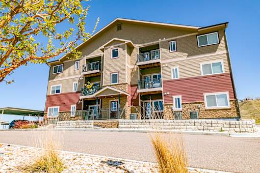 A large apartment building with a red and beige exterior and a balcony on the second floor.