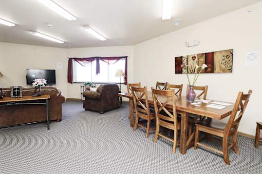A living room with a brown couch, a brown chair, a wooden table and chairs, and a television.