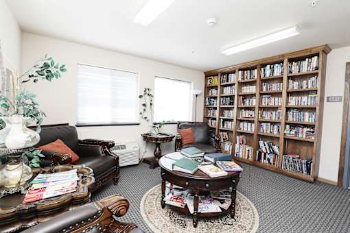 A living room with a leather couch, a coffee table, and a bookshelf filled with books.