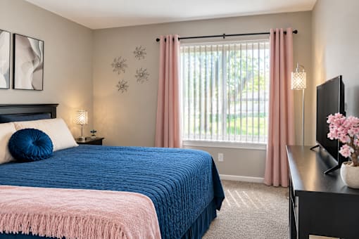 A bedroom with a blue bedspread and pink bedding.