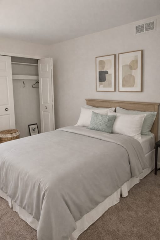 A bedroom with a bed, pillows, and two framed pictures on the wall.