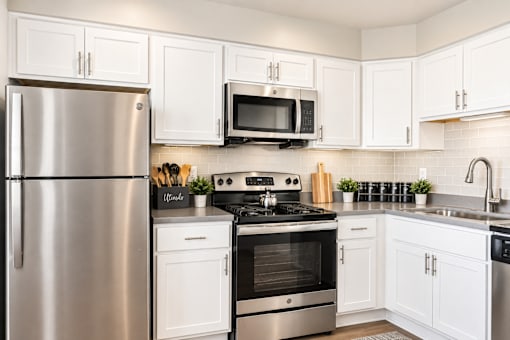 A modern kitchen with white cabinets and stainless steel appliances.