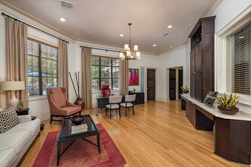A living room with a white sofa, a brown chair, a black coffee table, and a red rug.