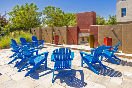 a group of blue chairs on a patio with a fire pit
