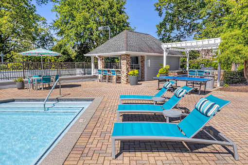 A pool area with sun loungers and a gazebo.