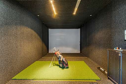 A person sitting on a green mat in a room with concrete walls.
