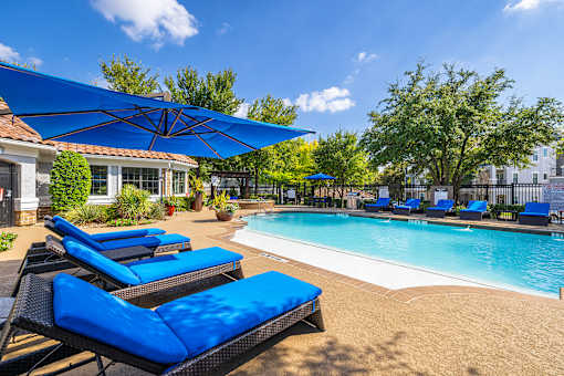 A pool area with blue lounge chairs and umbrellas.