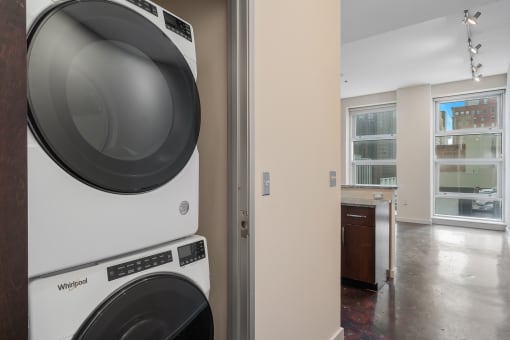 a washer and dryer in a laundry room with a kitchen in the background