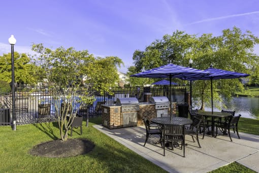 a patio with tables and umbrellas next to a body of water