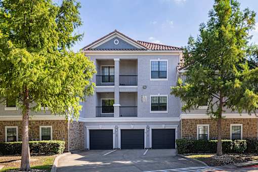 A two-story apartment building with a garage door and balcony.