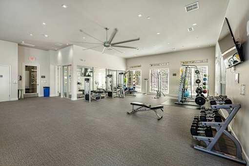 A spacious gym with a variety of equipment and mirrors on the walls.