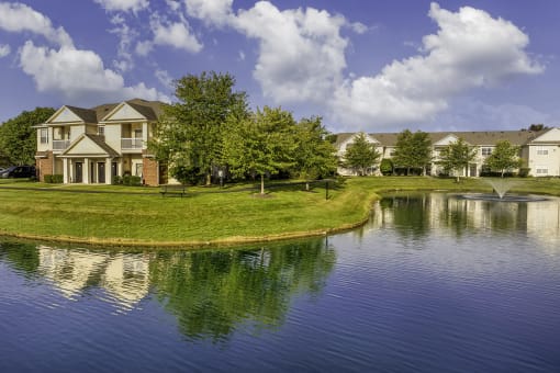 a pond in front of a house with a fountain