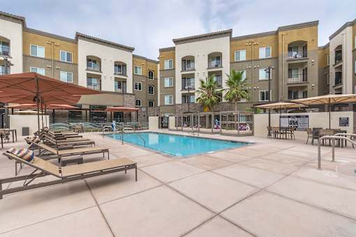 Resort-style swimming pool with lounge and cabana seating - Talavera Apartments