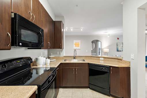 A kitchen with black appliances and brown cabinets.