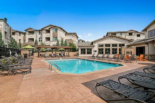 Resort-style swimming pool surrounded by lounge chairs - First and Main Apartments