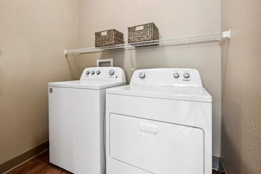 Two white front loading washing machines in a laundry room.