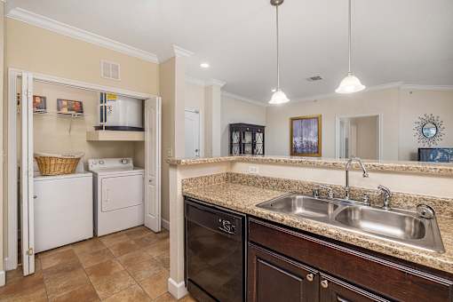 A kitchen with a black dishwasher and a white washing machine.