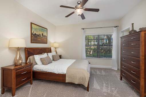 A bedroom with a bed, nightstand, and dresser.