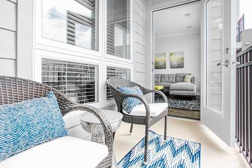 A white chair with blue pillow is in front of a white couch.