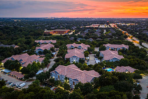 A sunset view of a residential area with houses and parked cars.