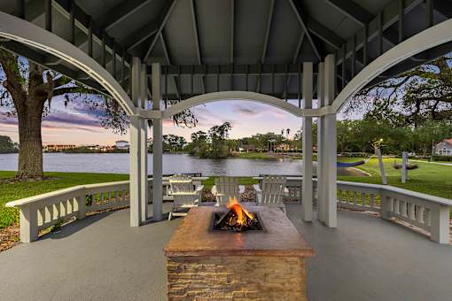 Lakeside gazebo with fire pit and seating area - The Colony at Deerwood Apartments