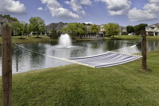 a hammock in front of a lake with a fountain