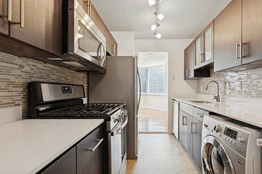 A modern kitchen with dark brown cabinets and stainless steel appliances.