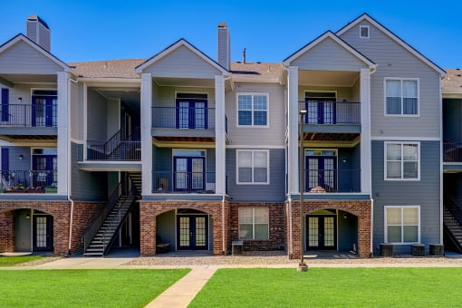 an exterior view of an apartment building with a lawn