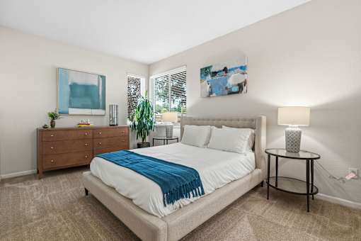 A bedroom with a bed, a nightstand, and a painting on the wall.