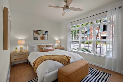A bedroom with a bed, a chair, and a ceiling fan.