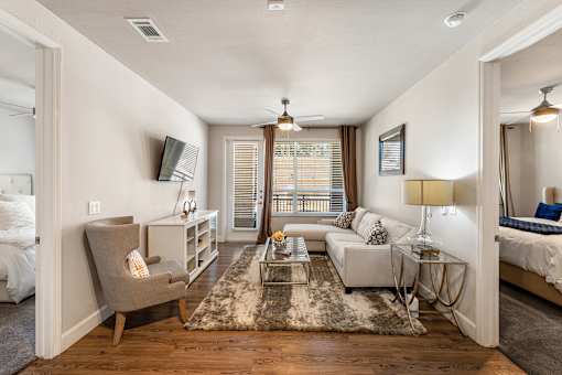 A well-lit, spacious living room with a grey chair and a white sofa.